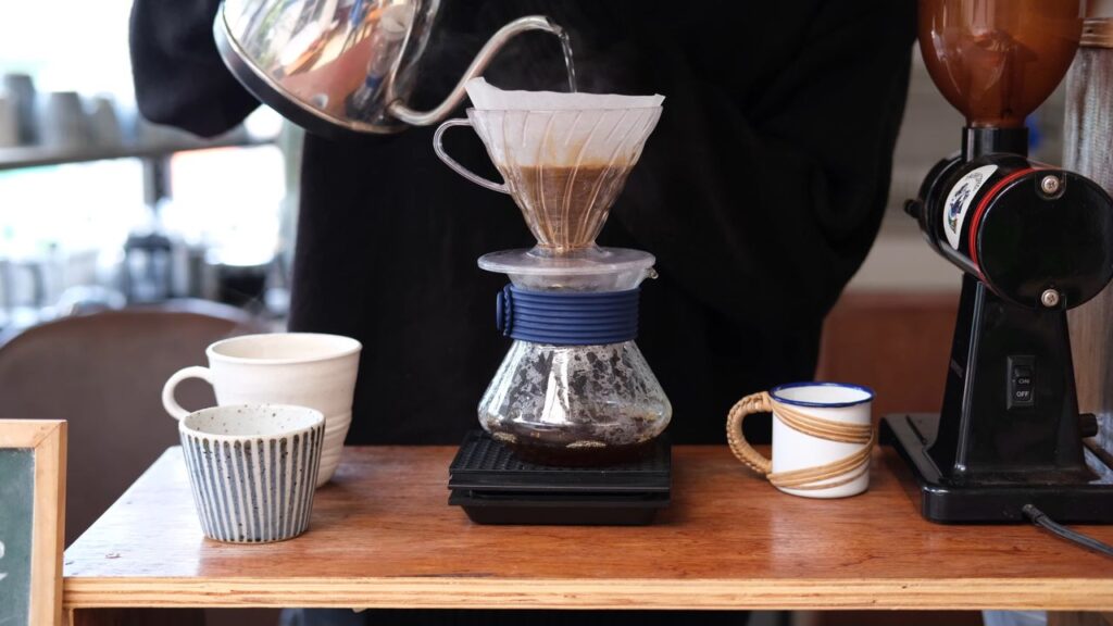 Close-up of a pour over coffee brewing process with cups and grinder.